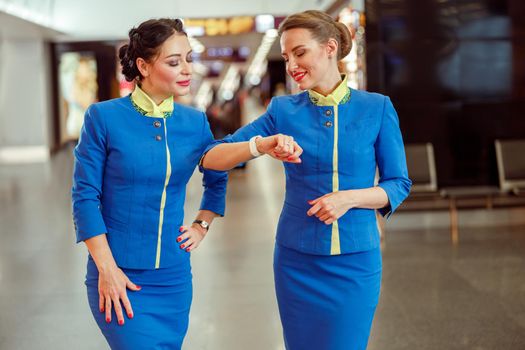 Female flight attendants checking time at airport