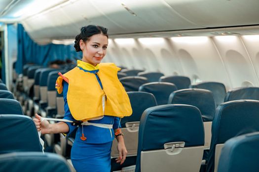 Stewardess demonstrating how to use life vest in airplane