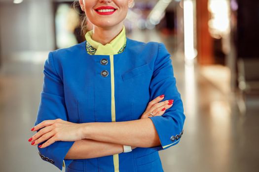 Joyful stewardess with arms crossed standing at airport