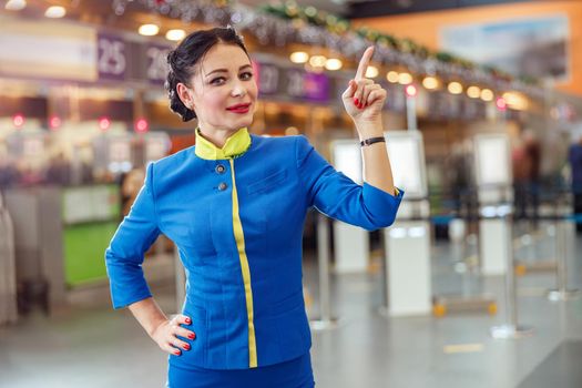 Woman stewardess pointing finger up in airport terminal