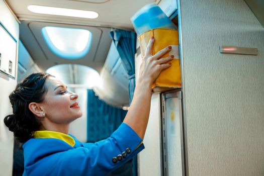 Stewardess putting bag in overhead shelf in aircraft cabin