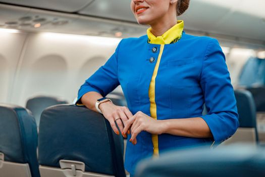 Smiling woman stewardess standing in aircraft passenger cabin