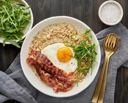 Oatmeal, fried egg and fried bacon. Brutal man sport breakfast. Hearty fat high-calorie breakfast,