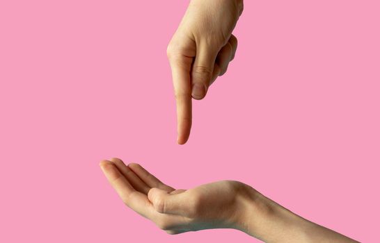 Close-up of women's hands, side view with the palm up, and the second hand points a finger at the palm. isolated on pink background