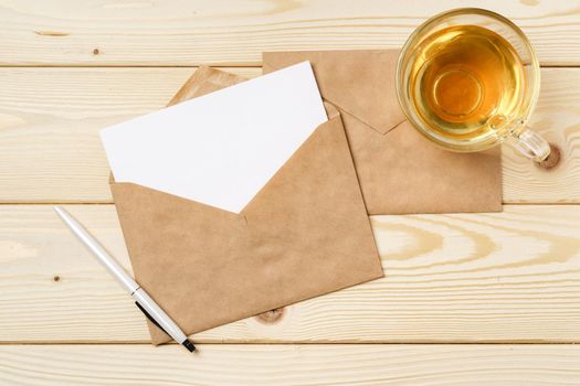 Envelopes with cup of tea on wooden table top