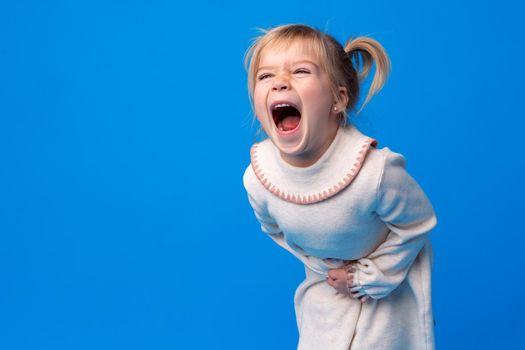 Cute little girl suffering from stomach ache on blue background