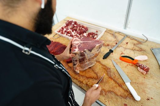 Close up of male hands cutting raw meat on wooden cutting board
