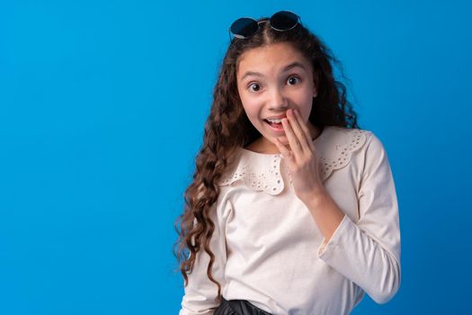 Shocked and surprised young teen girl against blue background