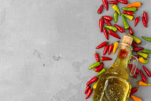 Bottle of olive oil and chili peppers on gray background