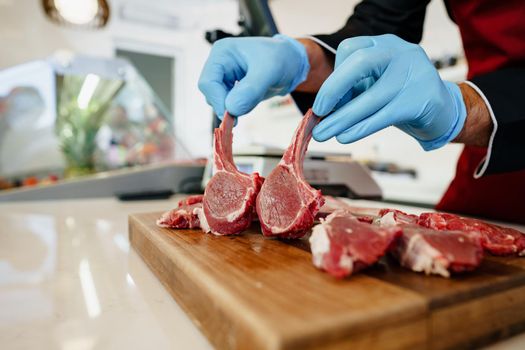 Close up of a butcher setting raw lamb ribs in a butcher shop