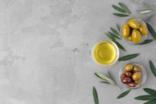 Flatlay composition of olives and olive oil on gray background