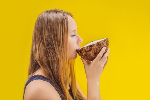 Young woman drinking coconut milk on Chafrom coconut on a yellow background