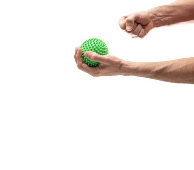Hand holding sphere with spines while right fist crushes it against white