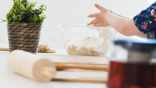 Hands of little girl mixing the dough for cookies in glass bowl