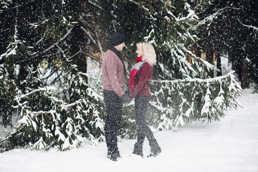 Couple looking each other in snowing forest.
