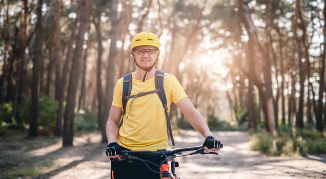 Cyclist standing with bike in forest