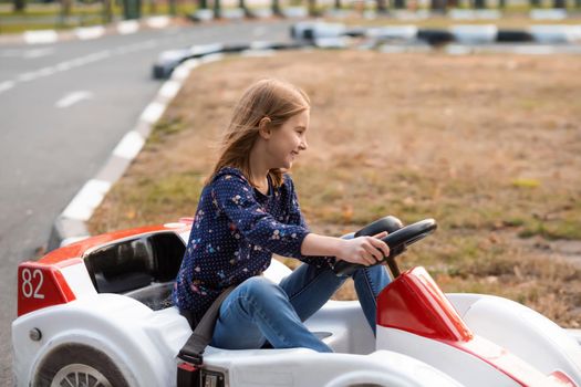 Happy little girl driving kart in park