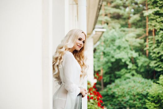 Gorgeous blondie bride walking at balcony and waiting for her groom.