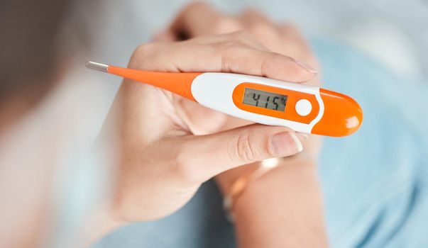 It can be worrying to see a temperature spike up. Shot of a woman holding a digital thermometer that reads 41.5 degrees.