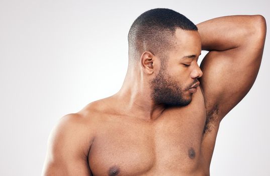 When you smell good, you feel good. Studio shot of a handsome young man smelling his armpit against a white background.