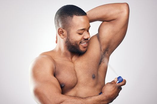 Clean is the way to go. Studio shot of a handsome young man spraying deodorant on his armpit against a white background.