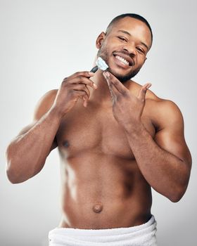 Shaving can do wonders to how you look. Studio portrait of a handsome young man shaving his facial hair against a white background.