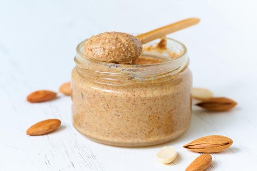 nut butter, crunchy and stir, white wooden table, glass jar, side view, close up