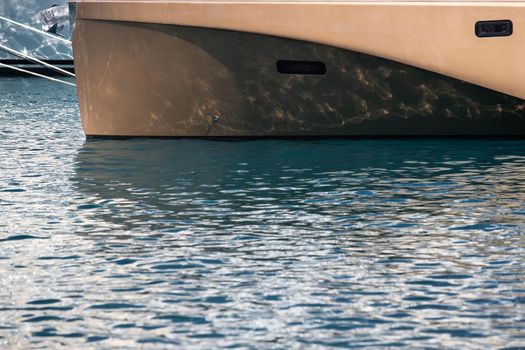 The mesmerizing reflection of the water on the glossy side of a huge yacht anchored, chrome details