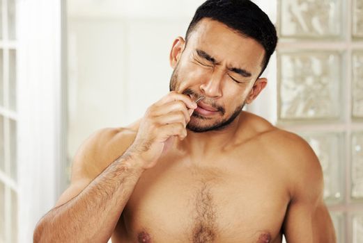 I think I should invest in a nose trimmer. Cropped shot of a young man using tweezers to pluck his nose hair.