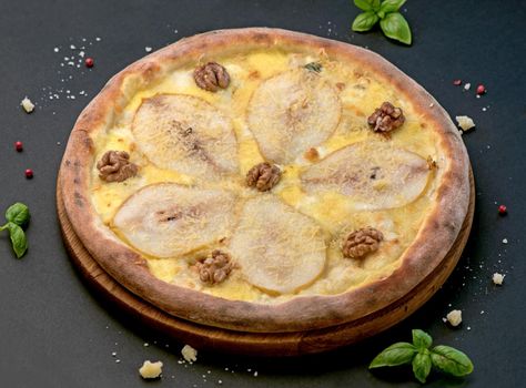 Fruit homemade sweet pear pizza with cheese and nuts, Rustic Italian savory food with pastry dough, top view, copy space