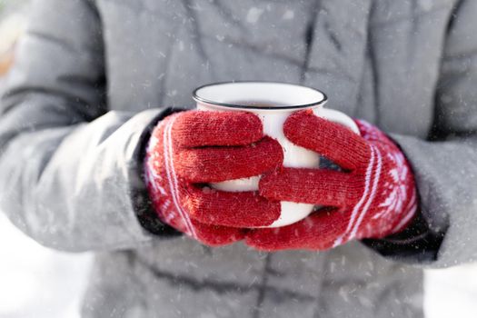 Hands in gloves holding cup