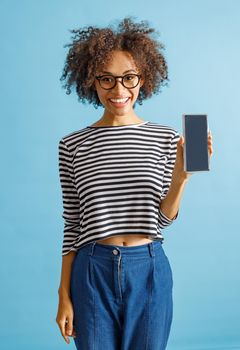 Cheerful woman with cellphone standing in studio