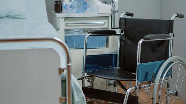 Close up of wheelchair in hospital ward for healthcare diagnosis and treatment. Nobody in bed at intensive care with oxygen tube and heart rate monitor for assistance and recovery.