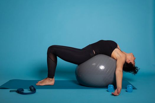 Personal trainer woman sitting on pilates fitball practicing abs exercise