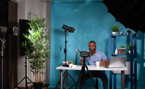 Wide view of vlogging studio setup with smiling vlogger interacting with audience sitting at desk