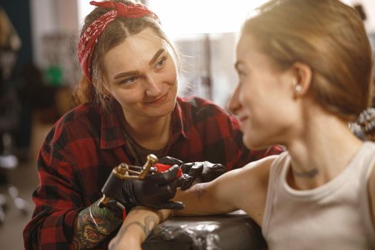 Portrait of smiling tattoo artist looking at client while working