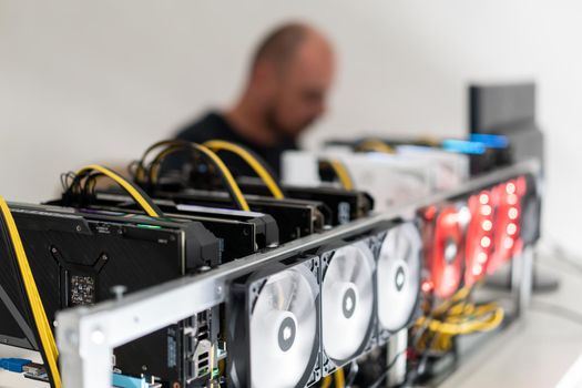 Young programmer adjusting cryptocurrency mining rig to optimal operational settings