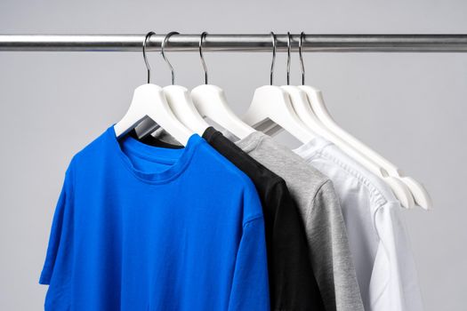 Clothes hang on clothing rack over white background.