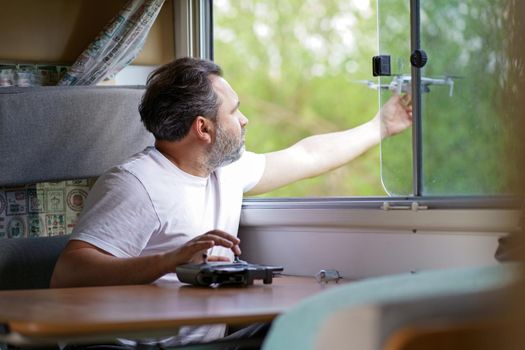 a man controls a drone from the window of a motorhome