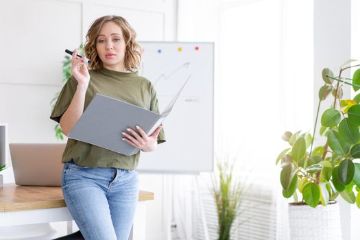Businesswoman holding folder for paper write marker thinking dreaming standing near office table