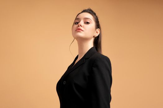 Young business woman close up portrait dressed black jacket standing studio isolated on color background.