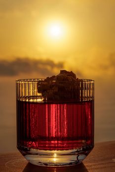 Negroni cocktail in an old-fashioned garnished glass against orange sunset.