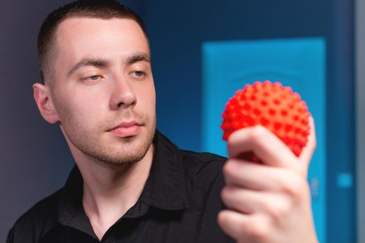 Portrait of a young caucasian doctor physiotherapist massage therapist with a massage ball in his hand. Myofascial release and massage ball copy space