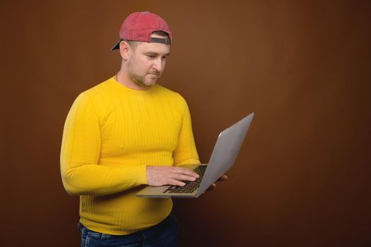 A man uses a laptop in the studio. Chubby man with his laptop stands in the studio