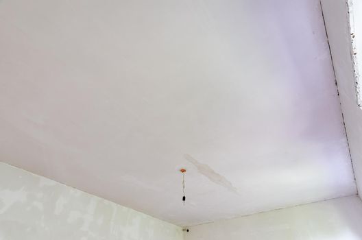 Plastered ceiling in the room, stains from flooding from above are visible on the ceiling
