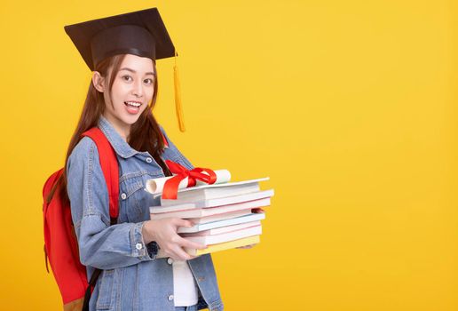Happy Asian girl college student in Graduation cap smiling and holding books