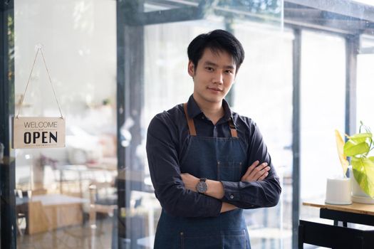 Portrait of Asian Man barista cafe owner smile while cafe open. SME entrepreneur seller business concept.