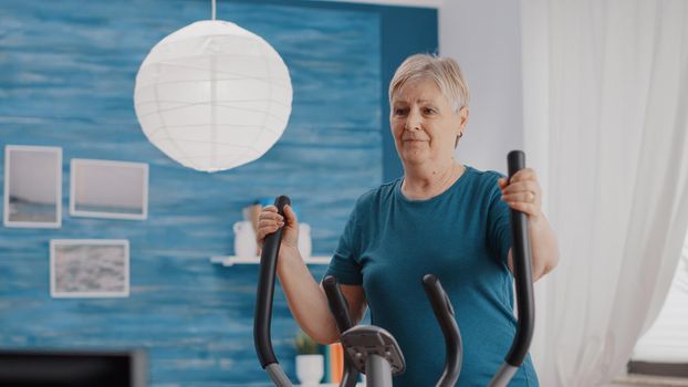 Close up of retired woman riding stationary bicycle at home