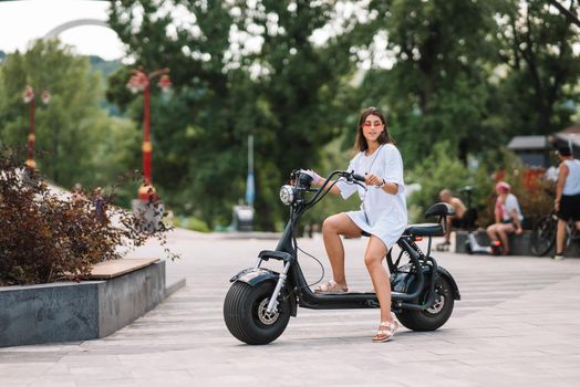 Young beautiful woman and an electric scooter, ecological transport