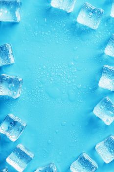 Ice made of cubes lined up with drops on a blue background with free space